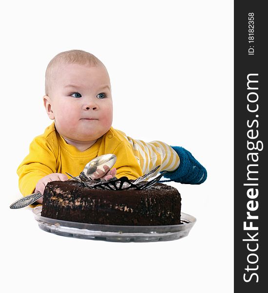 The baby with a big spoon in hand wants to eat chocolate cake