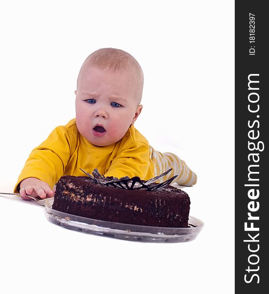 The baby with a big spoon in hand wants to eat chocolate cake