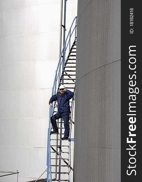 engineer, worker, standing on stairs of giant fuel-storage tank. engineer, worker, standing on stairs of giant fuel-storage tank