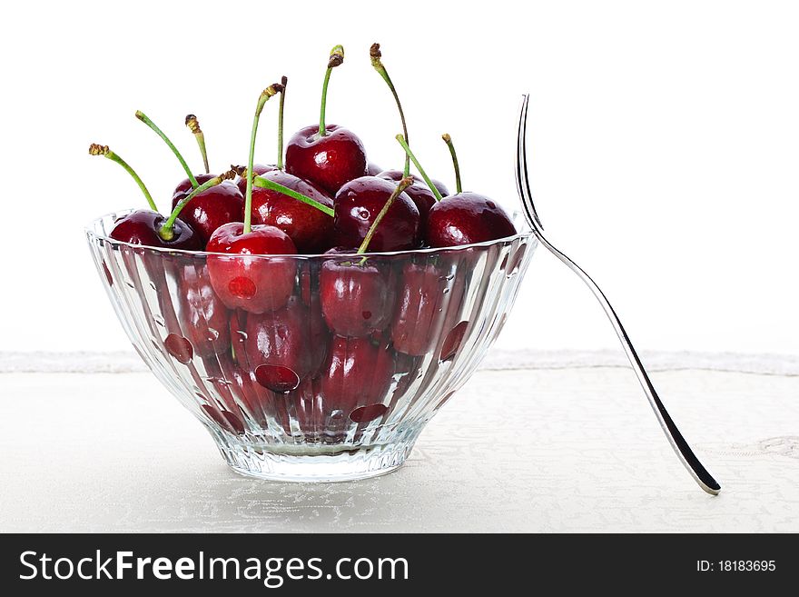 A bowl of fresh cherry with one fruit fork. A bowl of fresh cherry with one fruit fork.