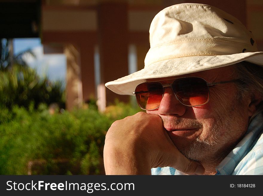 Portrait of a sixty something man with sunglasses and hat in a tourist resort. Portrait of a sixty something man with sunglasses and hat in a tourist resort