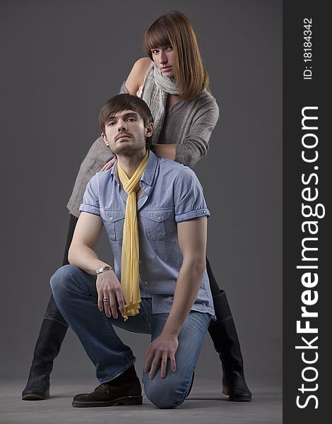 Man and woman posing in fashion clothes over grey background. Man and woman posing in fashion clothes over grey background