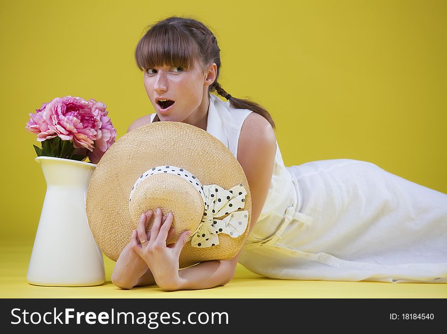 Surprised woman with hat and flowers over yellow background