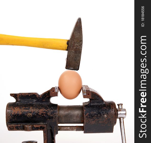 Egg trapped in the old rusty metalwork vice, on a white background