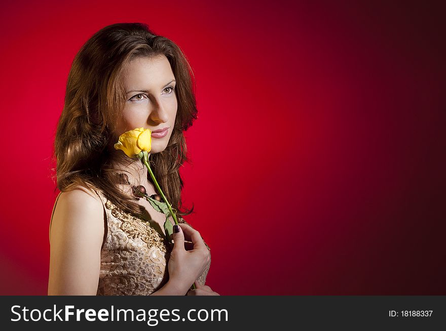 Young girl playing with a yellow rose recived for valentine's day; isolated on a red background
