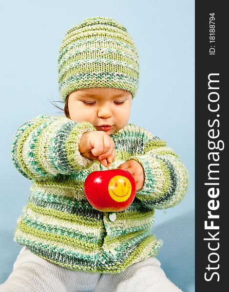 A young Boy is eating a smiling Apple. A young Boy is eating a smiling Apple