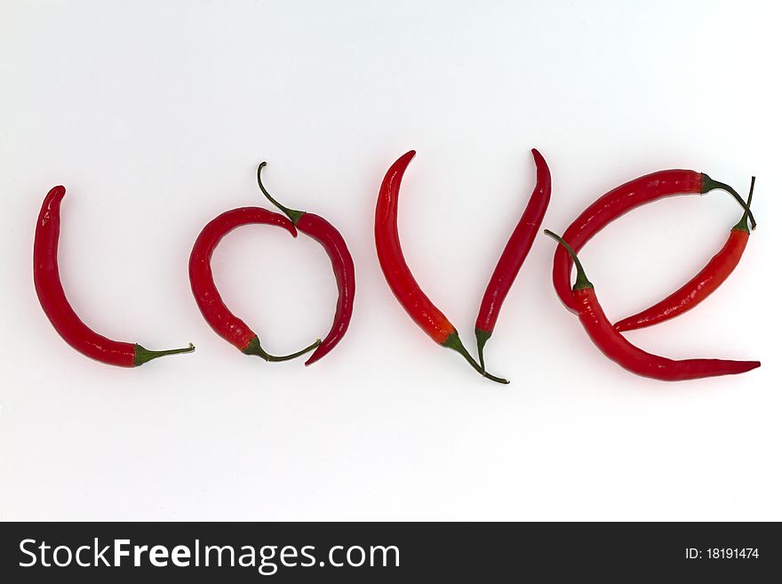 Red hot chili peppers arranged as the word LOVE on white background. Red hot chili peppers arranged as the word LOVE on white background