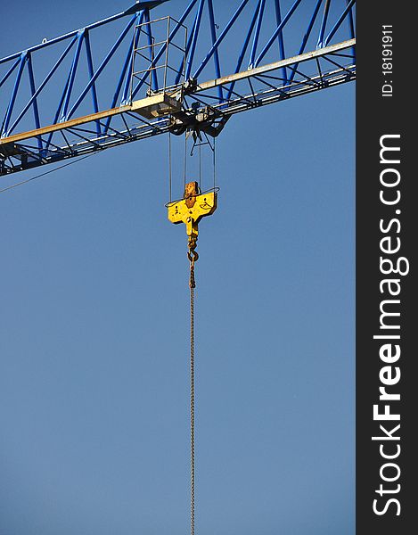 Closeup of yellow jib crane against blue sky. Closeup of yellow jib crane against blue sky