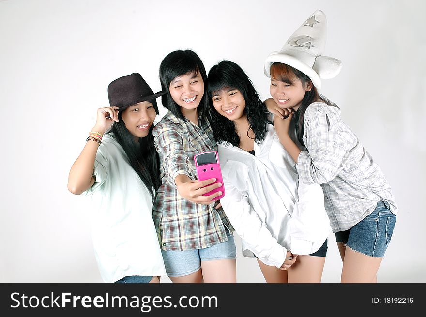 Four teenage girls take pictures using a camera phone. Four teenage girls take pictures using a camera phone