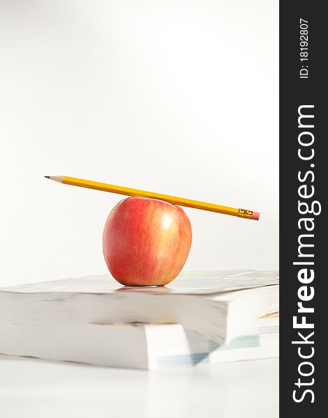 A Pencil on top of an Apple and books. A Pencil on top of an Apple and books