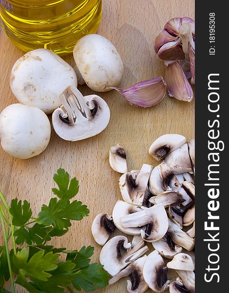 Mushrooms, whole and rolled, with garlic, parsley and olive oil on wood. Mushrooms, whole and rolled, with garlic, parsley and olive oil on wood