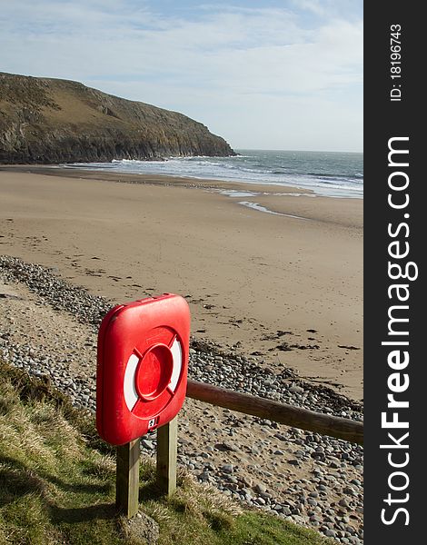 A red container, life saving equipment, placed by a beach with sand, sea and cliff. A red container, life saving equipment, placed by a beach with sand, sea and cliff.