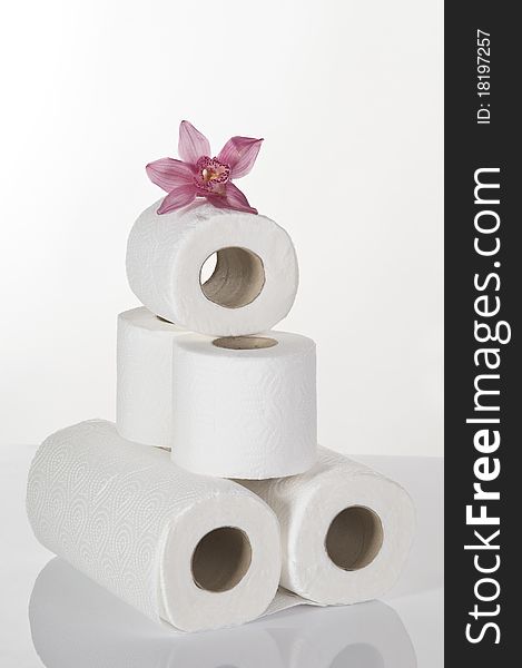 Concept still life with toilet paper and pink orchid over white background. Concept still life with toilet paper and pink orchid over white background