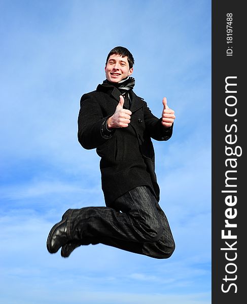 Young man jumping with thumbs up on blue sky. Young man jumping with thumbs up on blue sky