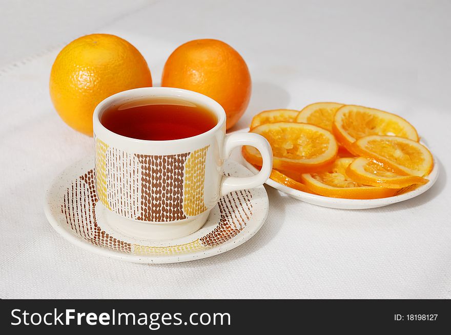 Tea drinking with delicious slices of candied orange and two oranges