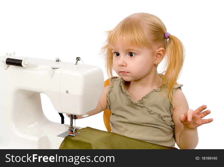 The little girl is sewing on the sewing machine and wonders. The little girl is sewing on the sewing machine and wonders