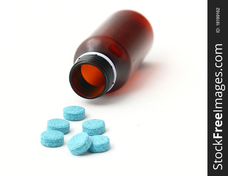 Empty brown medicine bottle and scattered blue pills isolated on white background. Empty brown medicine bottle and scattered blue pills isolated on white background