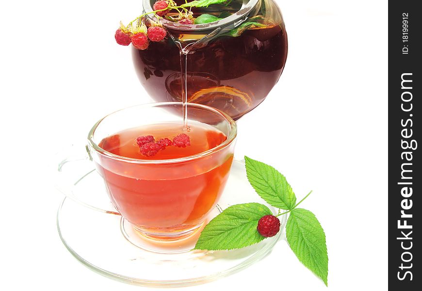 Pouring fruit tea with raspberry berries in teapot and cup. Pouring fruit tea with raspberry berries in teapot and cup