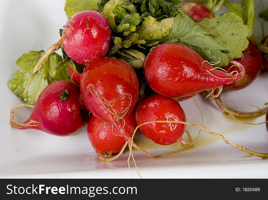 A bundle of red radishes on white plate.