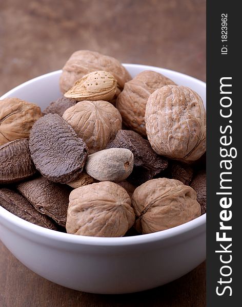 A bowl of mixed nuts on an aged, old-fashioned wooden table/cutting board. A bowl of mixed nuts on an aged, old-fashioned wooden table/cutting board.