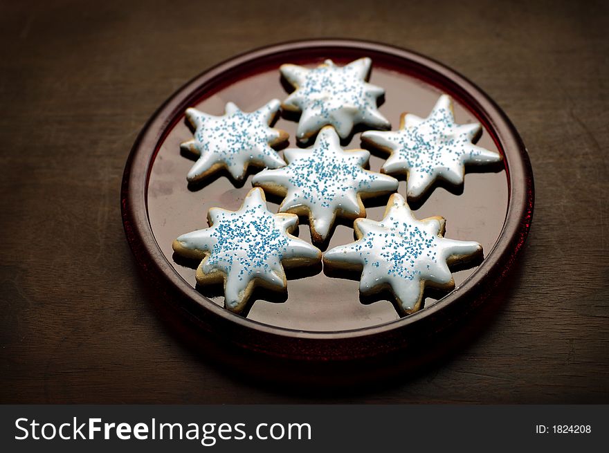 A plate full of iced sugar cookies in the shape of snowflakes. A plate full of iced sugar cookies in the shape of snowflakes.