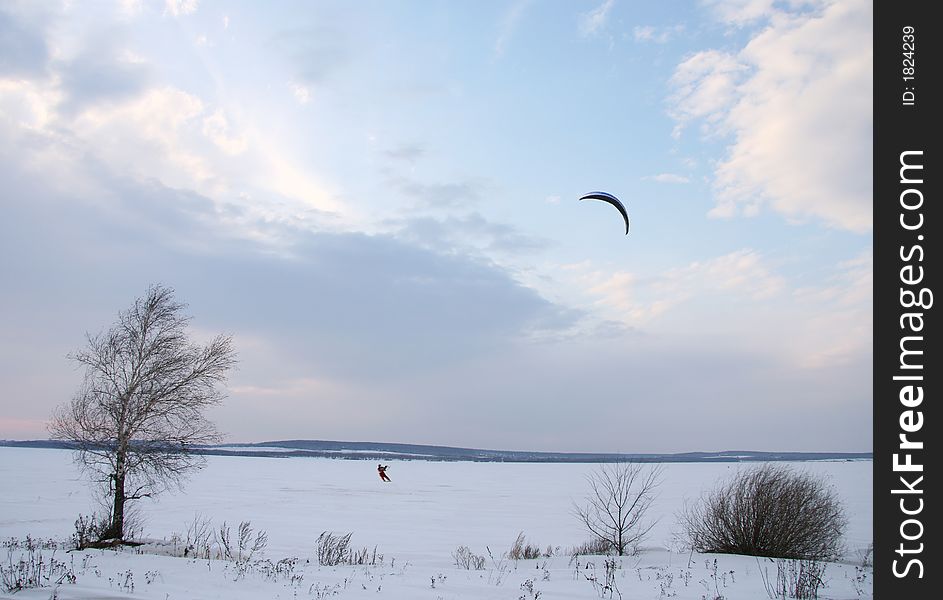 The skier with a parachute on winter, the covered ice lake.