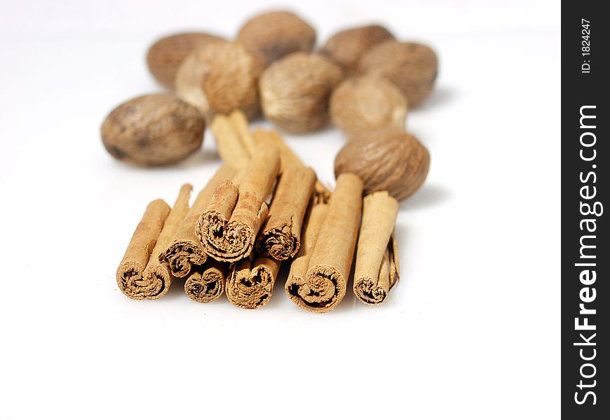 Cinnamon stick and whole nutmeg seed pods on white background