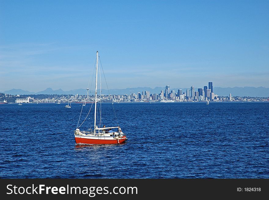 Red sailboat sailing away from Seattle, WA