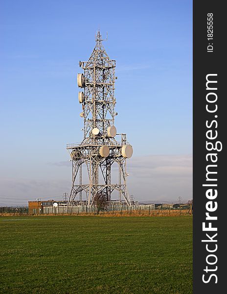 Photo of a mobile phone mast against a clear blue sky in late afternoon light.