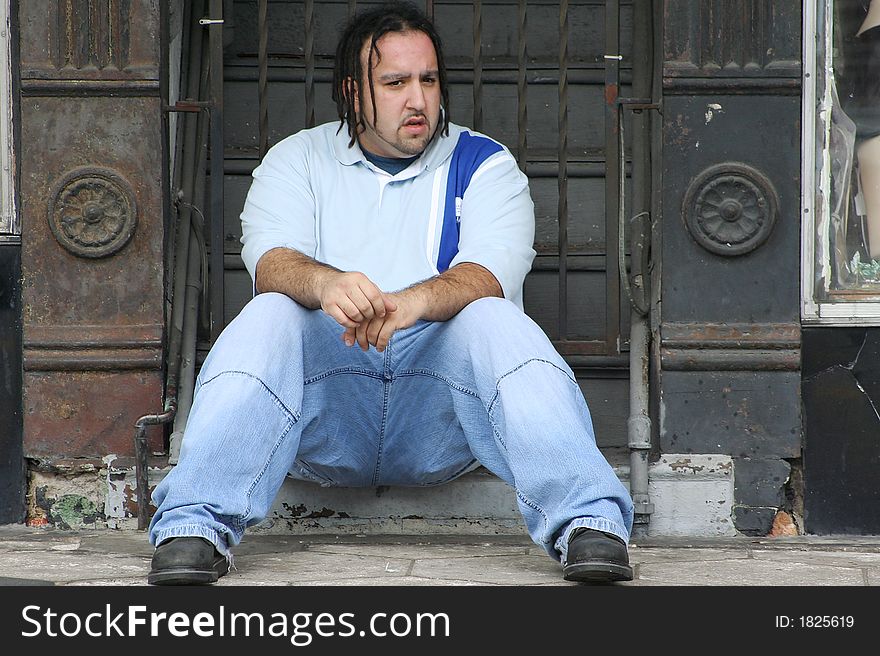 Photo of a young man sitting on the steps to a building. Photo of a young man sitting on the steps to a building