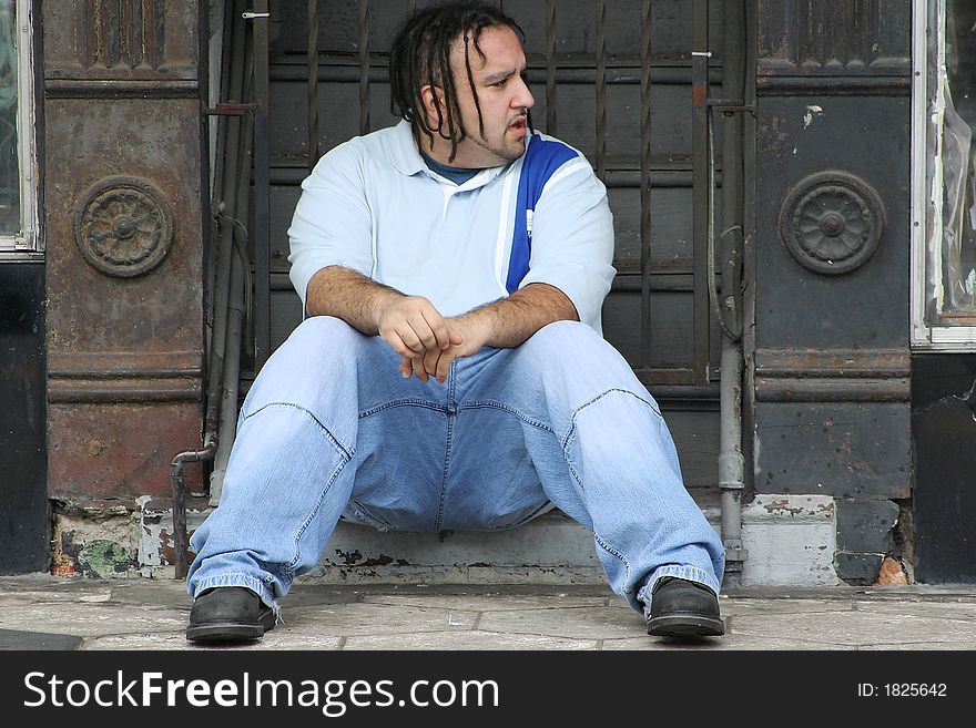 Photo of a young man sitting on the steps to a building. Photo of a young man sitting on the steps to a building