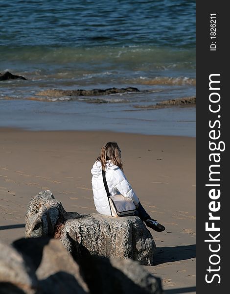 Woman sitting on rocks at the beach. Woman sitting on rocks at the beach