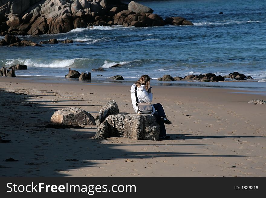 Woman sitting on rocks at the beach. Woman sitting on rocks at the beach