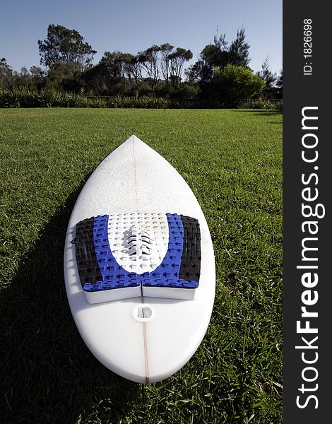 White Surfboard (Shortboard) With Three Fins Lying On A Green Grass Field