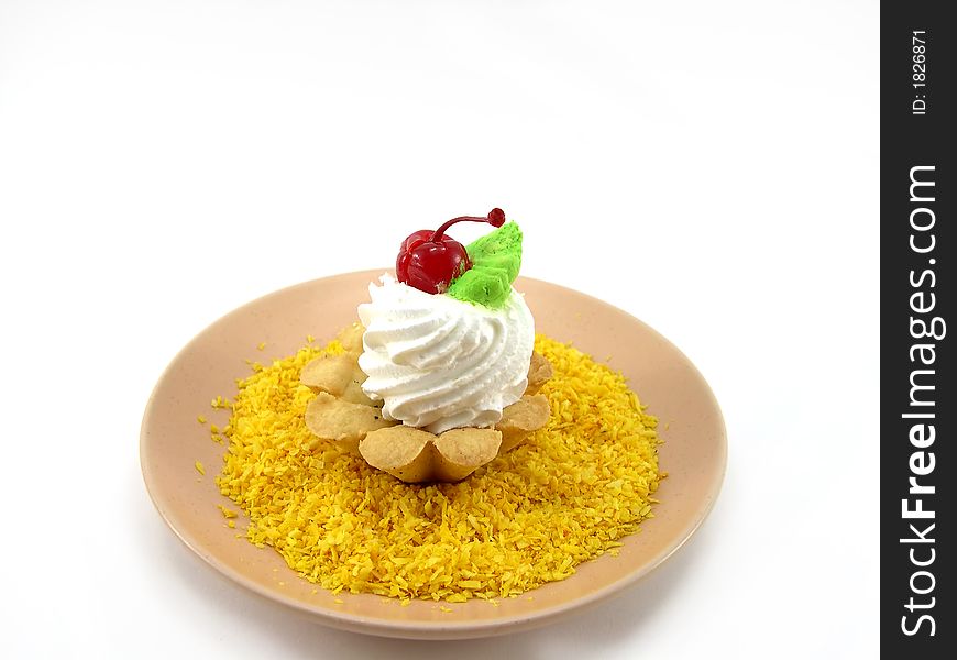 Beautiful cake as a basket with a cherry on a plate in a yellow coconut shaving on a white background