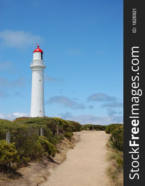 Path to white lighthouse against blue sky