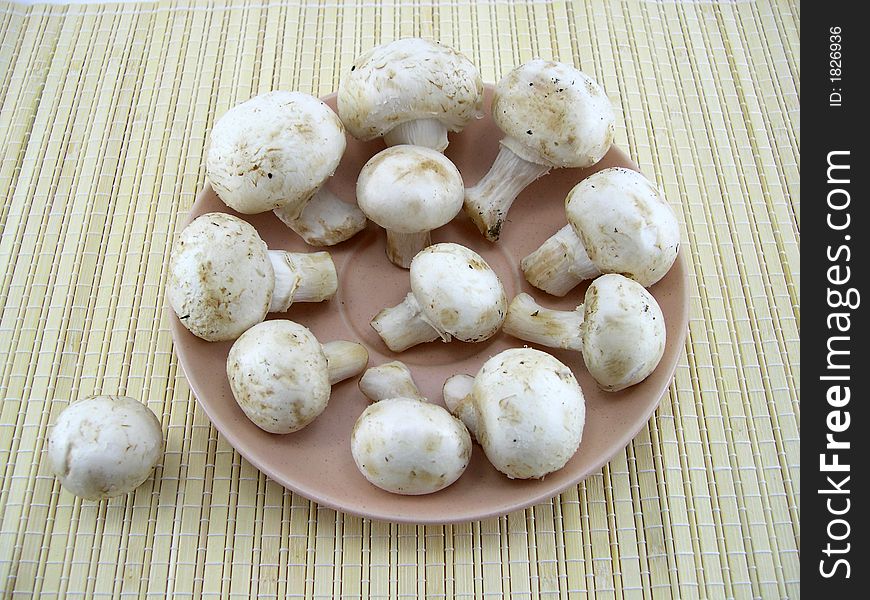 Beautiful white mushrooms champignons on a background of a bamboo napkin