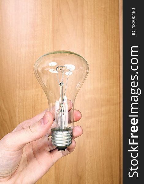 Electric light bulb on wood background with hand for environment and saving concept