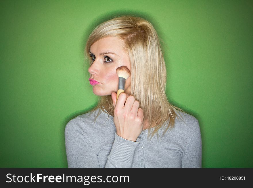 Woman preparing her make-up and hair before the party , on green background. Woman preparing her make-up and hair before the party , on green background