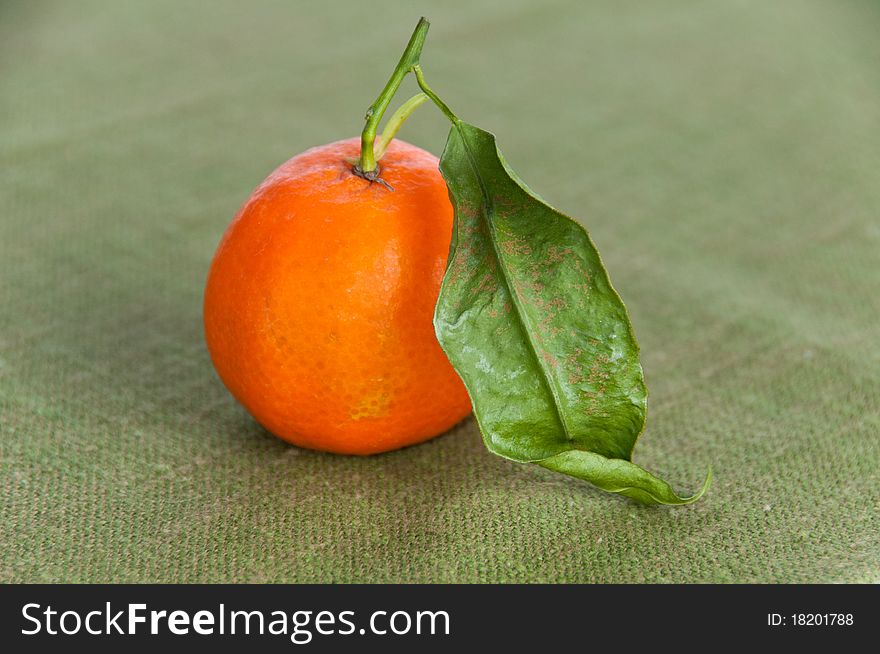 Single ripe orange on green napkin