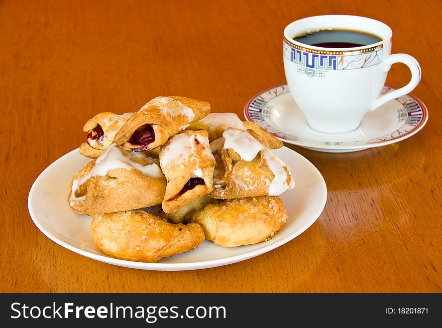 Plate of fresh golden brown assorted pastry with a cup of aromatic coffee on old wooden table. Plate of fresh golden brown assorted pastry with a cup of aromatic coffee on old wooden table