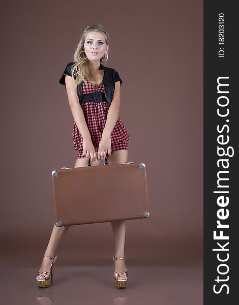 Emotional girl with a suitcase, on a brown background