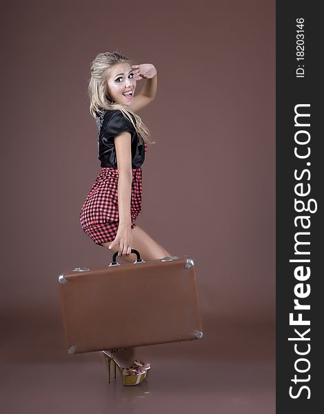 Emotional girl with a suitcase in hands, on a white background