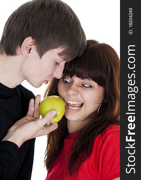 Cheerful young couple eats one green apple. Cheerful young couple eats one green apple