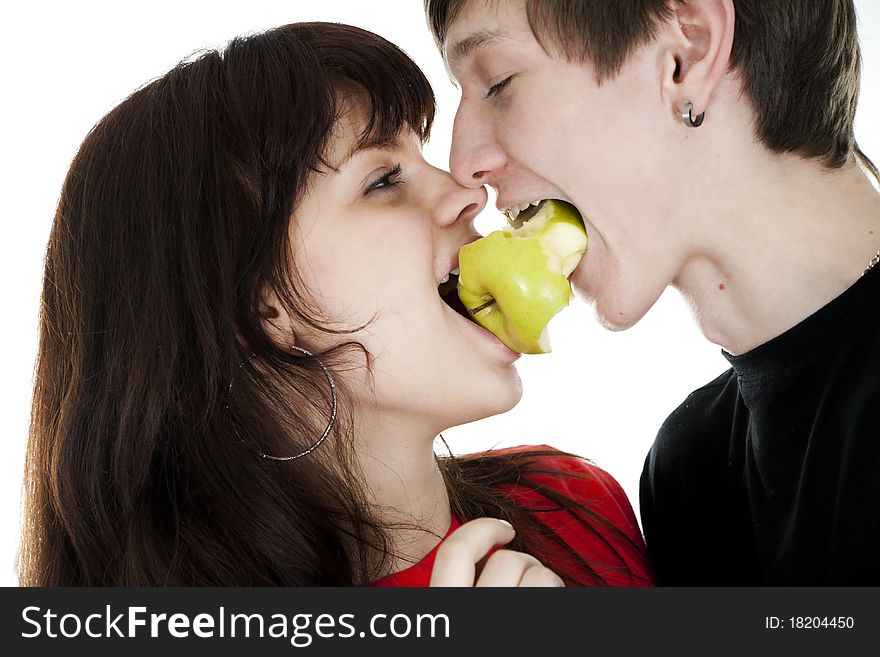 Cheerful young couple eats one apple