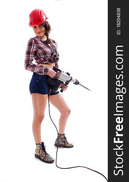 Beautiful young girl with a red helmet standing with drill in her hands. Beautiful young girl with a red helmet standing with drill in her hands