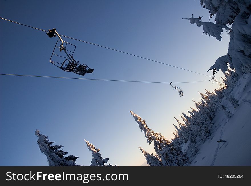 Chairlift (ski-lift) in winter mountains forest. Nice day with clear blue sky and lot of snow on trees. Chairlift (ski-lift) in winter mountains forest. Nice day with clear blue sky and lot of snow on trees.