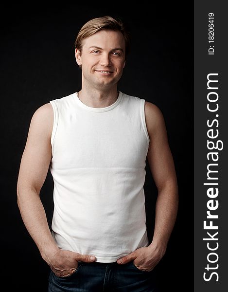 Smiling young guy in the white shirt on the black background