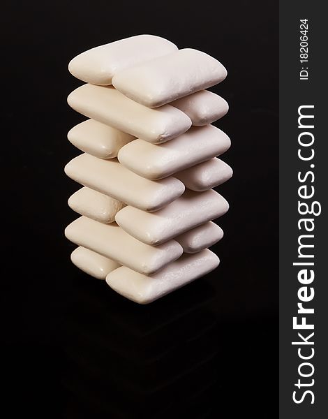 Stacked white spearmint chewing gums isolated over back background. Stacked white spearmint chewing gums isolated over back background.