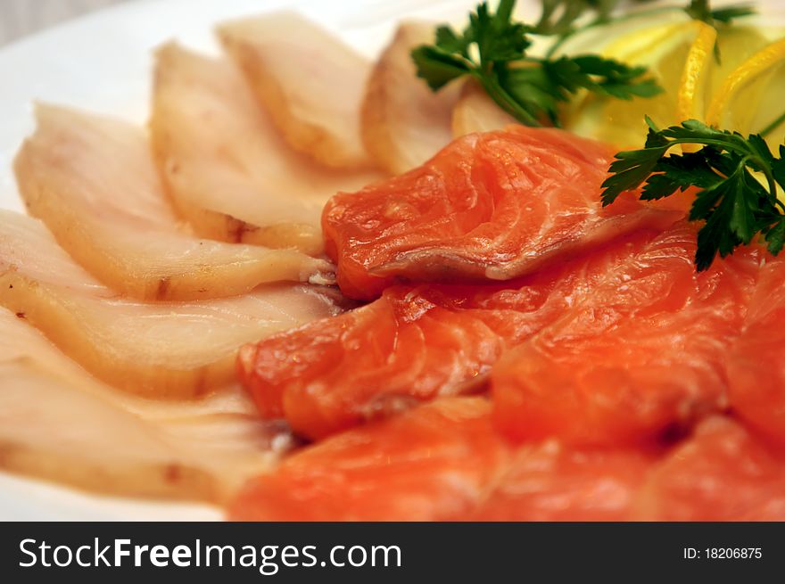 Slices of sturgeon and salmon with lemon and parsley